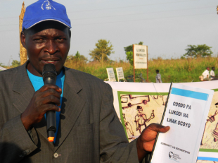 Vincent Oyet, a member of the Lukodi CORE (Community Reconciliation) Team holds a copy of 'Ododo Pa Lukodi' (the stories of Lukodi) during the launch of Community-Led Documentation in Lukodi.