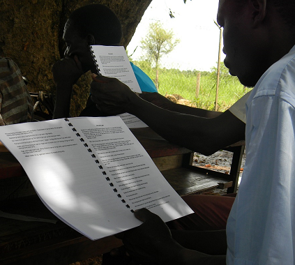 A man reads from written documentation 'Ododo pa Lukodi' (stories of Lukodi) during a Community Led Documentation community outreach in Lukodi, Gulu district. 27 April 2013.