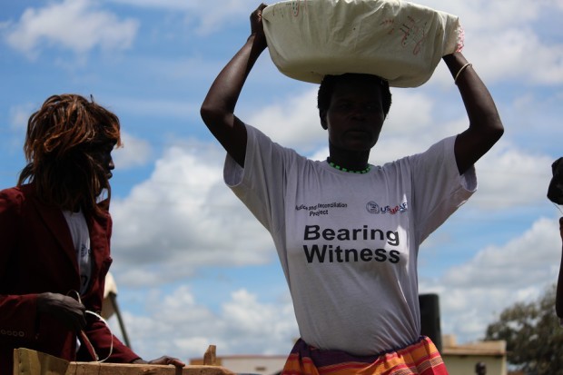 Limo Can Tek (of Pupwonya parish) performs a song and drama piece entitled "Kony Dwogo Lutino Gang" ("Kony return our children home"). This scene depicts an abducted person being forced to carry luggage after a rebel attack.
